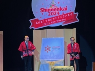 Sr. Nakasone, Presidente de APJ y el Sr. Araki, Presidente de la Comisión Conmemorativa del 125 aniversario de la inmigración japonesa al Perú con hapi rojo, vestimenta tradicional japonesa, develan el logotipo del 125 aniversario en el escenario