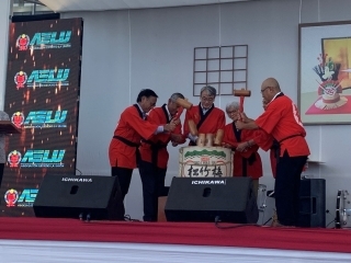 Los invitados con hapi rojo, vestimenta tradicional japonesa, están a punto de abrir el barril de sake en el escenario