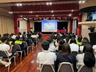 El material de la presentación proyectada en el fondo de la sala, con varios jóvenes sentados y a la espera para escuchar la presentación