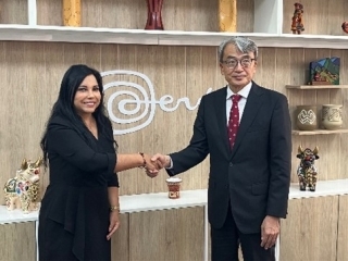 El Embajador YAMAMOTO estrecha la mano de la Ministra Galdo y se toman una foto delante del logotipo de turismo de Perú