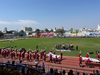 Los representantes de APJ desfilan en la pista atlética llevando el logo de los 125 años de Inmigración Japonesa al Perú.