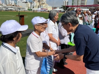 El Embajador Sr. YAMAMOTO entrega un recuerdo conmemorativo a un adulto mayor.