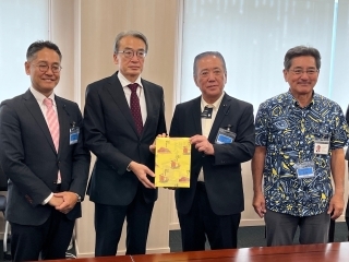 両側に議員がいる中央で中川議長が山元大使に記念品を手交