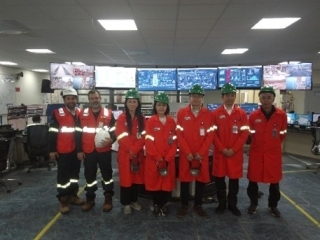 Foto grupal delante de los monitores que muestran diversos datos de la planta de Gas Natural Licuado.