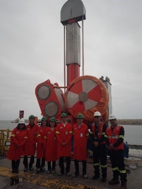 Foto grupal delante del equipo utilizado para asegurar las cuerdas de amarre de los buques de Gas Natural Licuado.