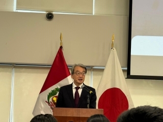 ペルーと日本の国旗の前で主催者を代表して挨拶する山元大使