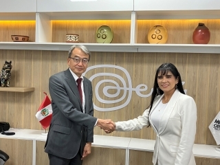El Embajador YAMAMOTO estrecha la mano de la Ministra León y se toman una foto delante del logotipo de turismo de Perú.