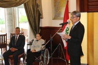 Señora TENYA y señor Tokumori sentados, atentos a las palabras de felicitaciones del Embajador que se encuentra de pie.