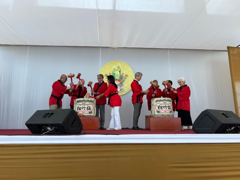 El Embajador y YAMAMOTO y los invitados están abriendo los barriles de sake en el escenario