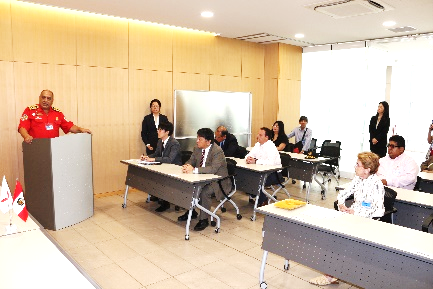 挨拶をするペルー消防団次官と挨拶を聞くその他の出席者たち