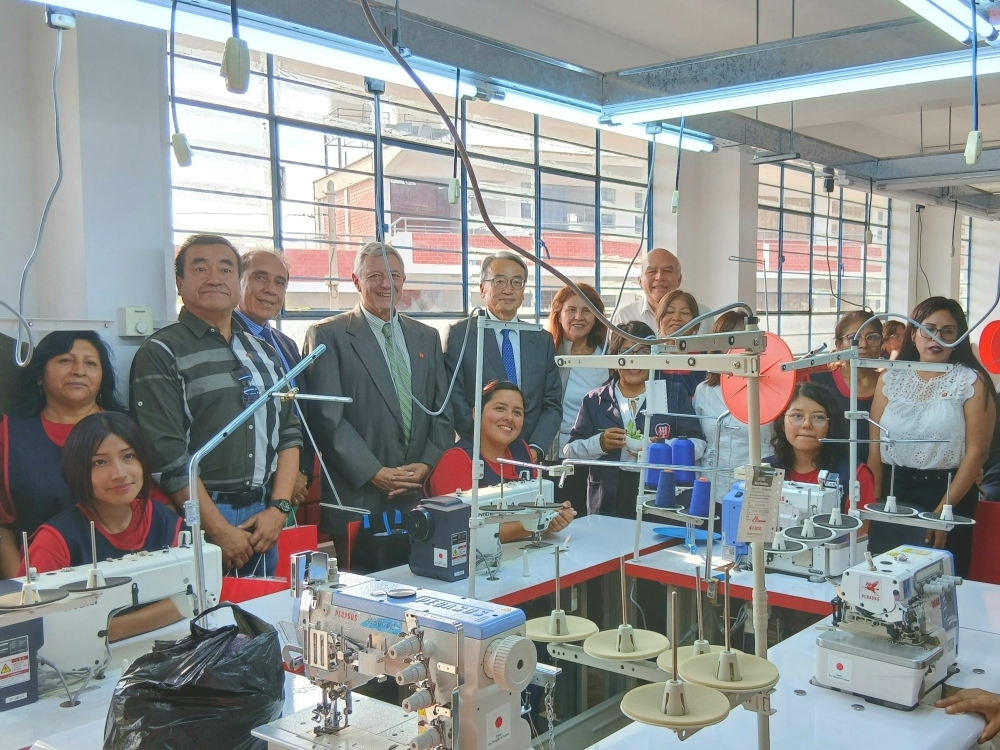 Foto conmemorativa con las estudiantes y el padre Ernesto Cavassa, Director de la Asociación Fe y Alegría del Perú frente a las máquinas de coser entregadas