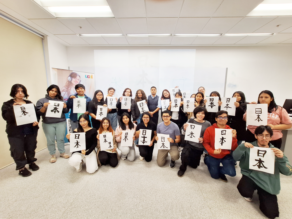 Los participantes juntos con los funcionarios de la embajada del Japón se tomaron una foto conmemorativa, mostrando el kanji que escribieron durante el taller de la caligrafía japonesa