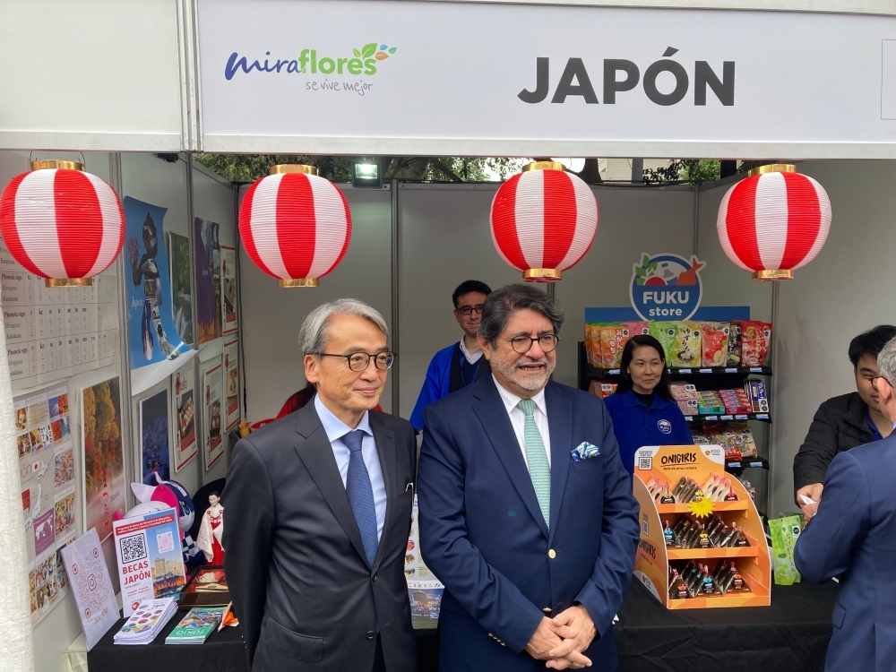 山元大使が、日本大使館のブースの前で、カナレス・ミラフローレス区長と記念写真を撮っている
