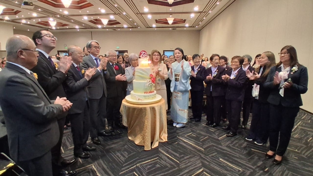El Embajador, su esposa y los asistentes al lado de la torta, cantando el 