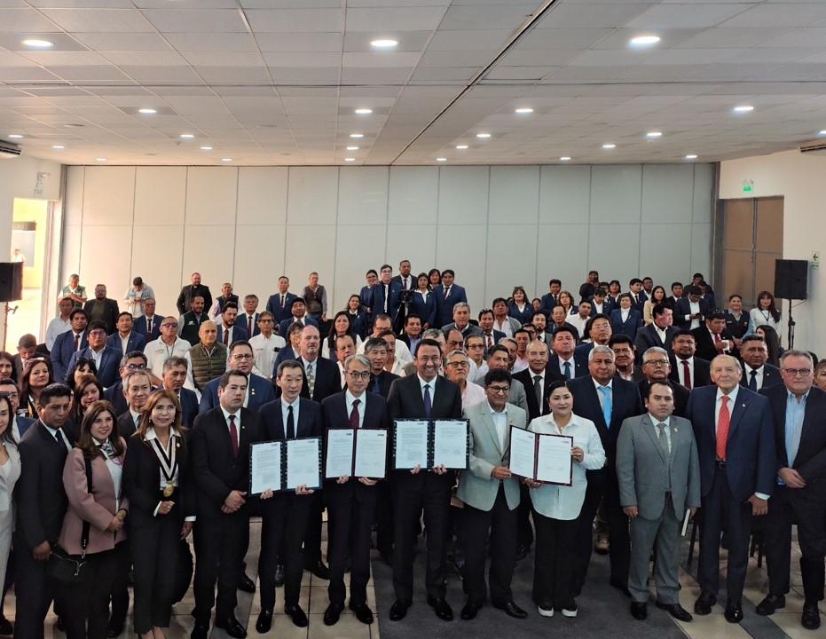 Foto grupal de los asistentes con los documentos firmados en el centro