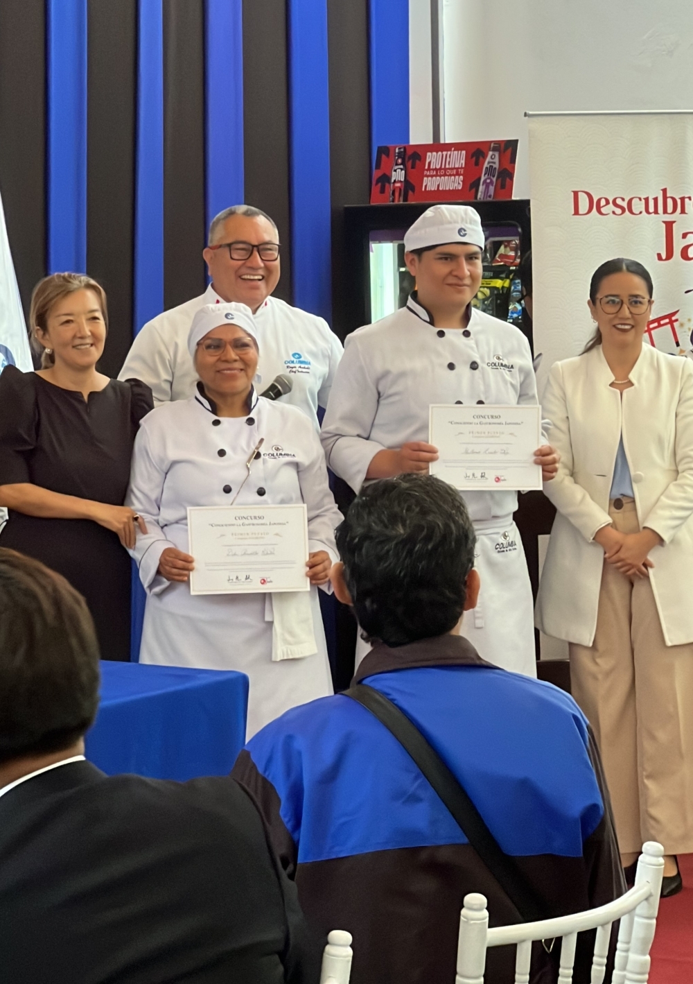 揚げ物部門で1位に入賞したコルンビア高等学院の学生2名が、賞状を見せながら記念撮影を行っている