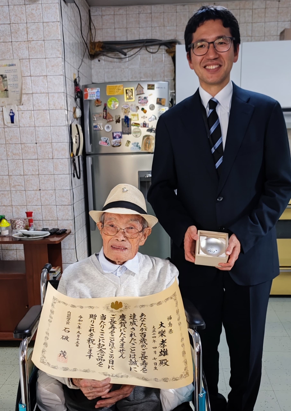佐藤領事が大楽孝雄氏に祝状を渡している。