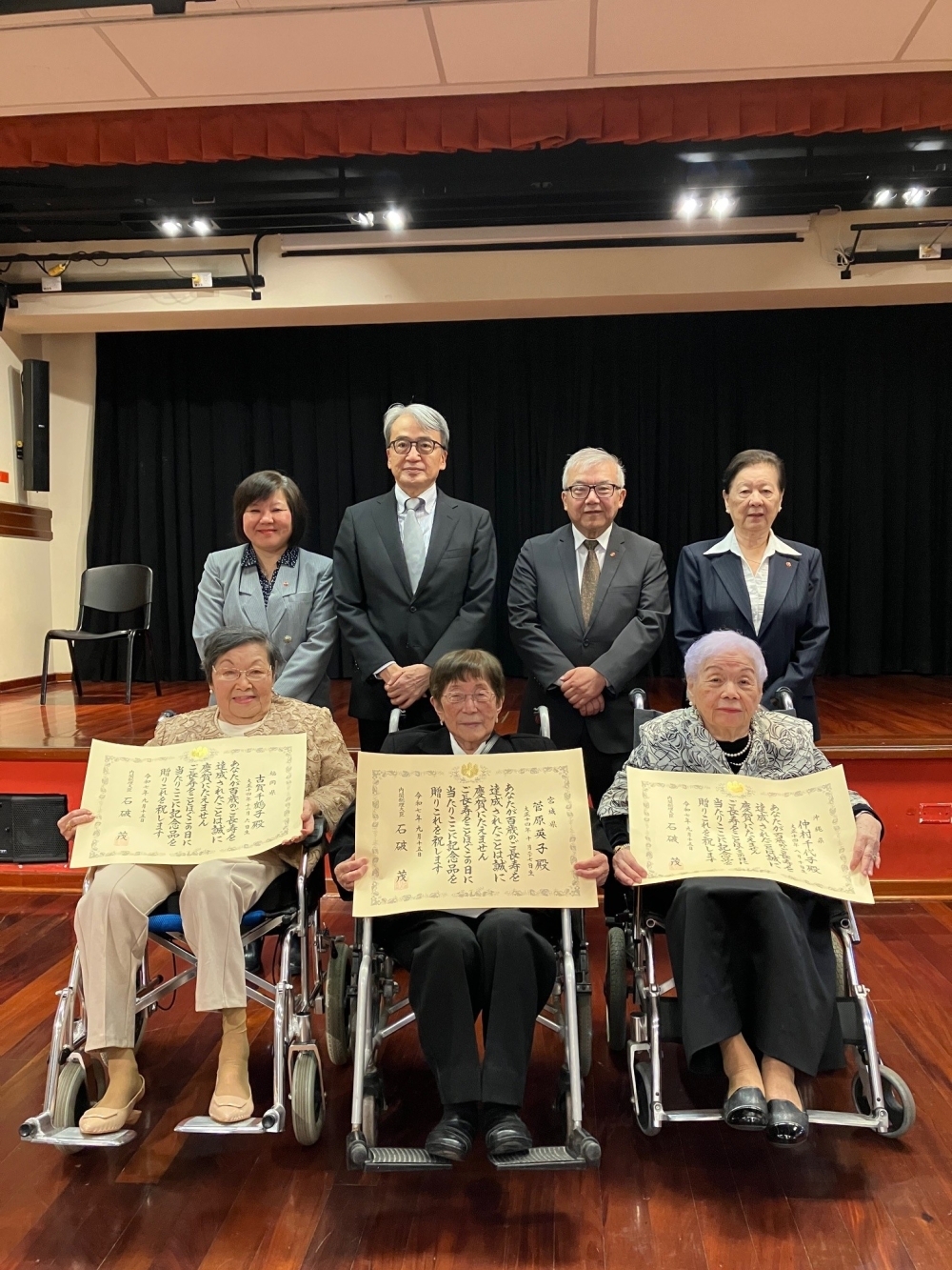 Foto  conmemorativa las señoras KOGA Chizuko, SUGAHARA Hideko y NAKAMURA Chiyoko con el embajador YAMAMOTO, el Presidente Igei de la Asociación Peruano Japonesa y otros invitados.