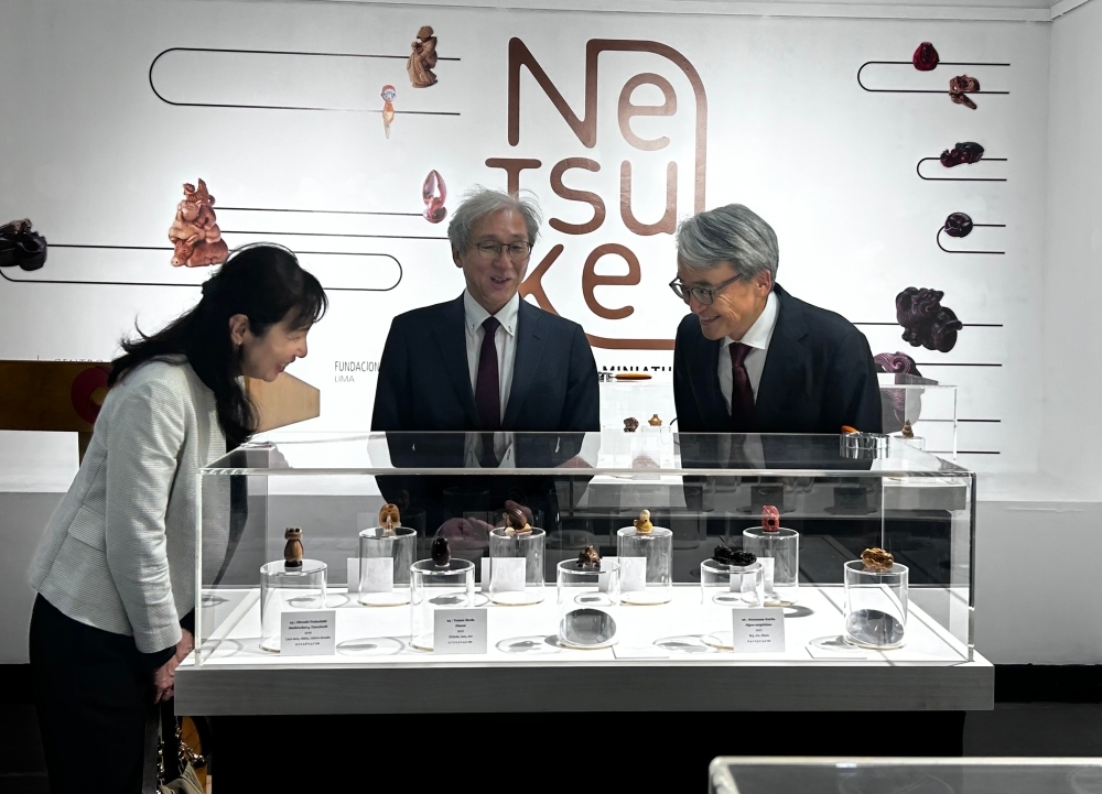 El embajador YAMAMOTO está realizando un recorrido de la exposición Netsuke junto con los asistentes.