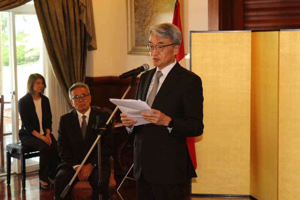 El señor Miyashiro sentado, atento a las palabras de felicitaciones del embajador que se encuentra de pie
