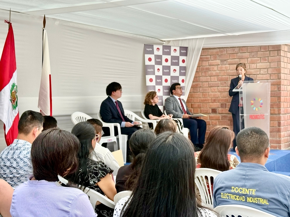 出席者の前で挨拶をする古川参事官