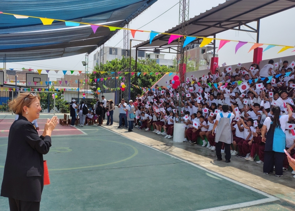La consejera FURUKAWA recibiendo la bienvenida de los niños que sostienen las banderitas de Japón