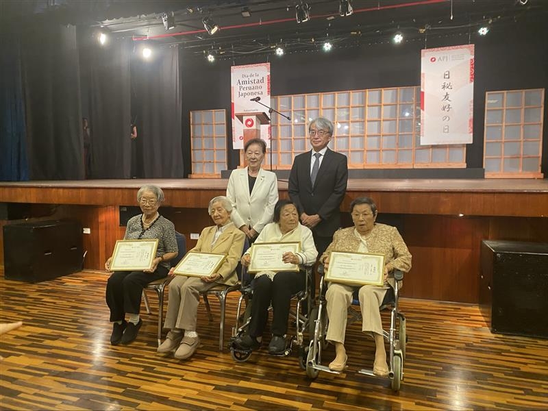 El embajador YAMAMOTO tomándose una foto con los adultos mayores Nikkei que recibieron reconocimiento.