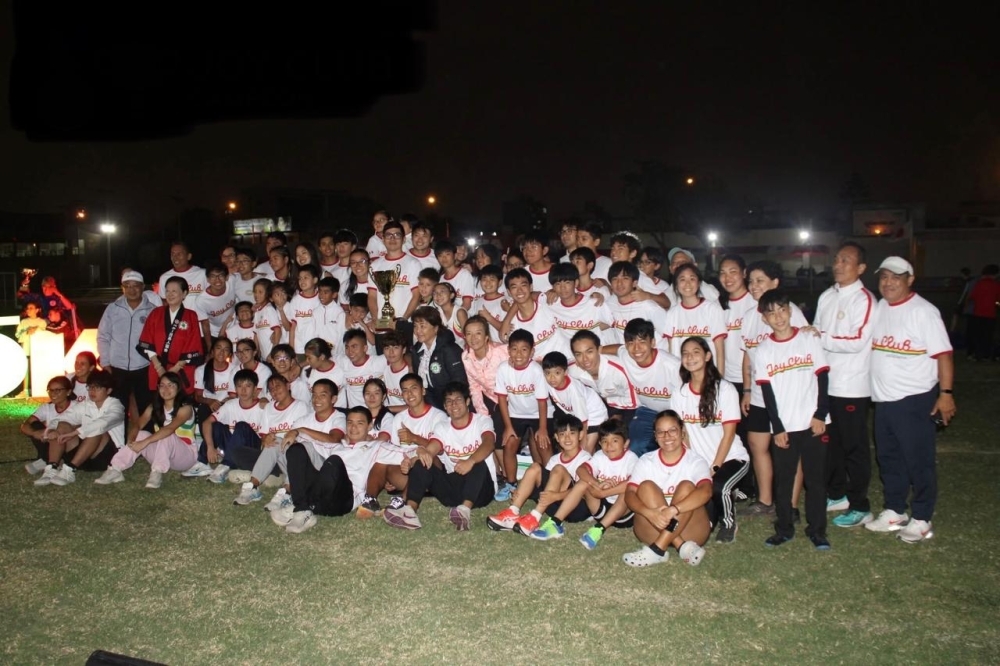 El equipo campeón celebrando junto con sus compañeros sosteniendo el trofeo