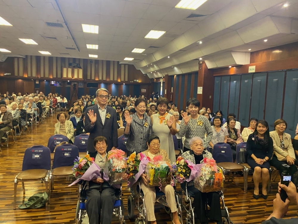 花と記念品を贈呈された100歳を迎えた高齢者との記念撮影